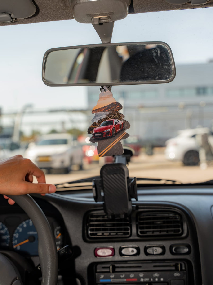 A cardboard air freshener in the shape of a little tree hangs from the rear-view mirror of the Suzuki.