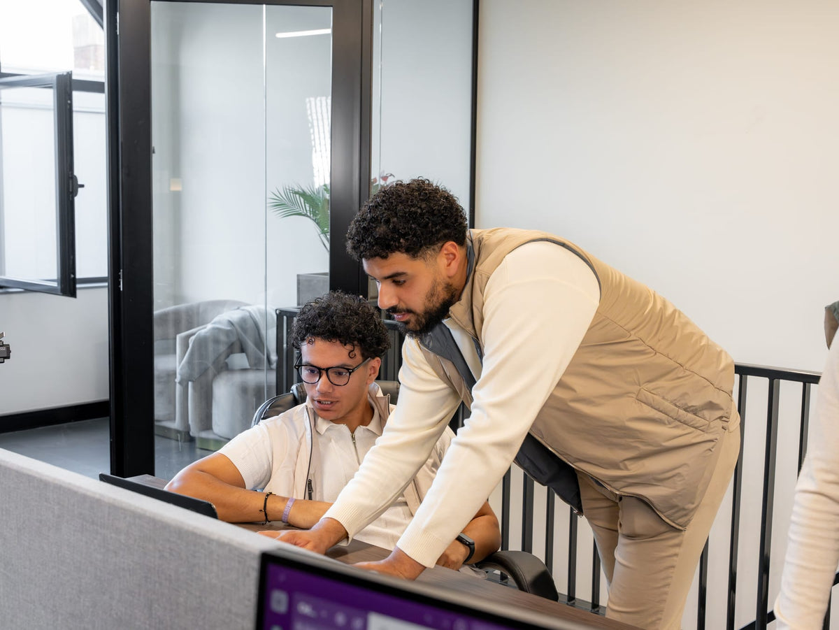 One of the founders leans over a colleague's desk.