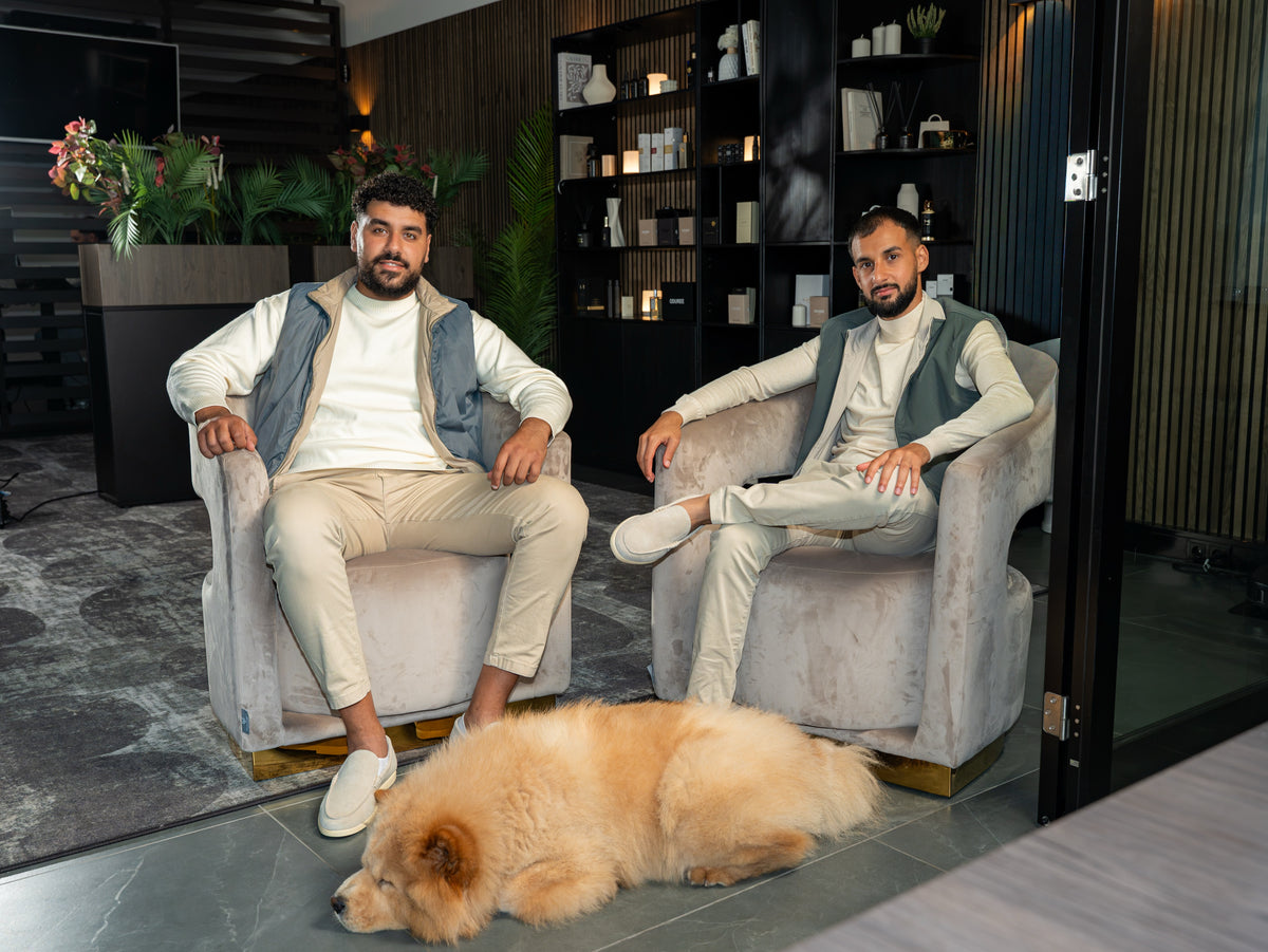 Marco and Kiro, the founders of Oduree, in armchairs in the lounge, with the dog at their feet.