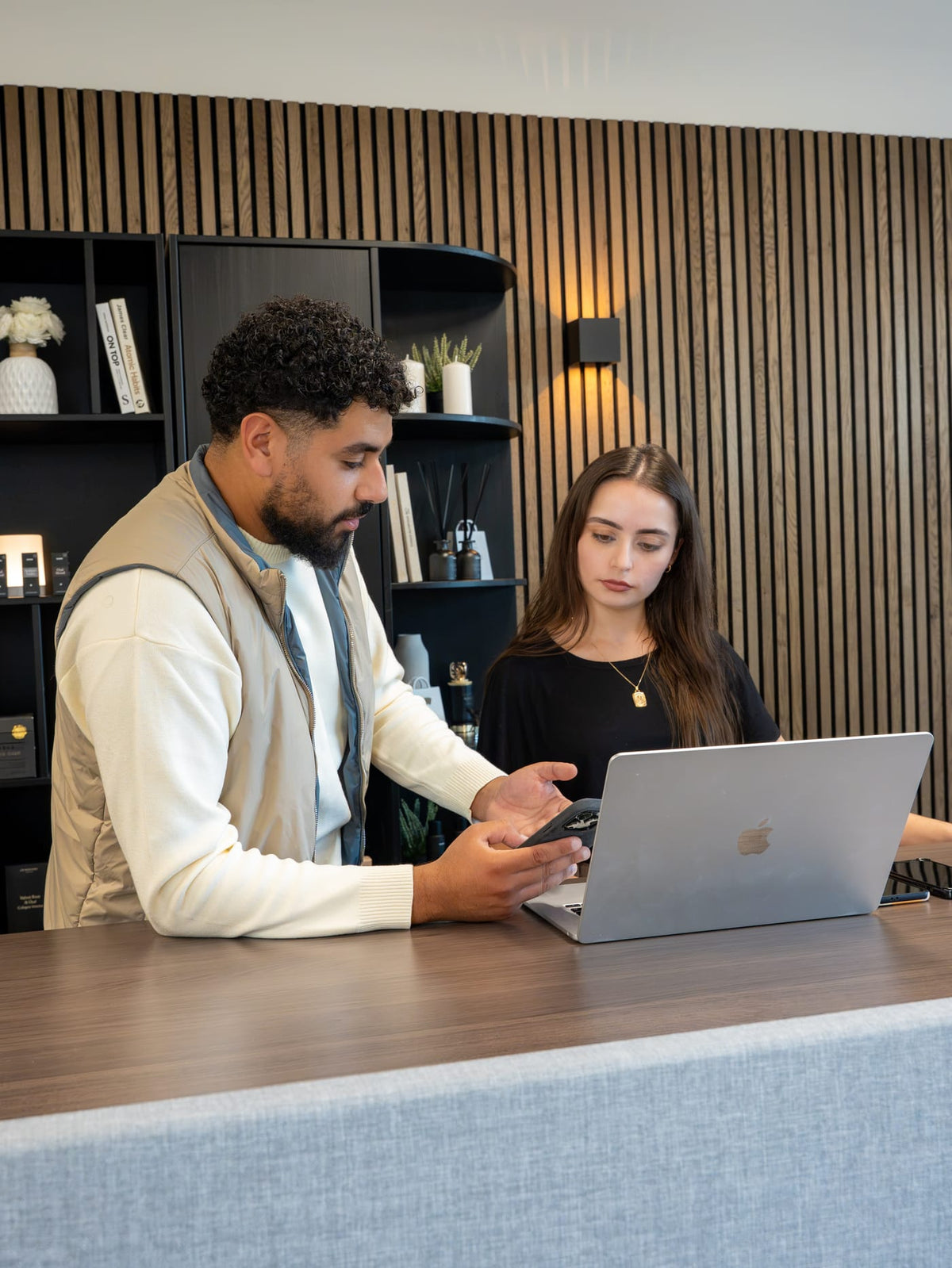 One of the founders talks things through with a colleague at the counter, beside a laptop.