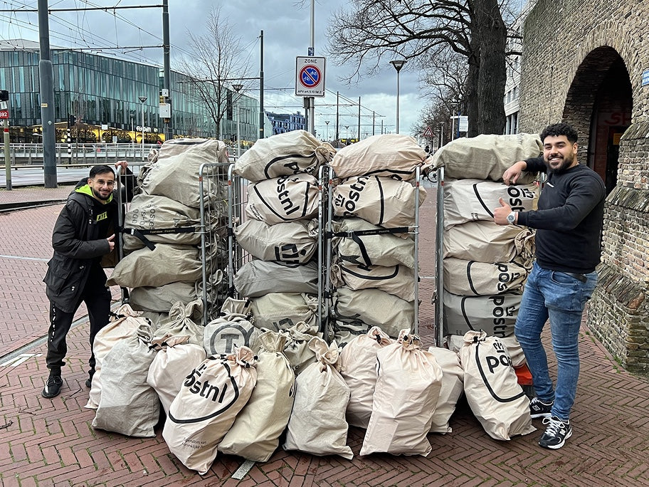 Marco en Kiro bij rolcontainers vol postzakken met bestellingen, Black Friday 2023