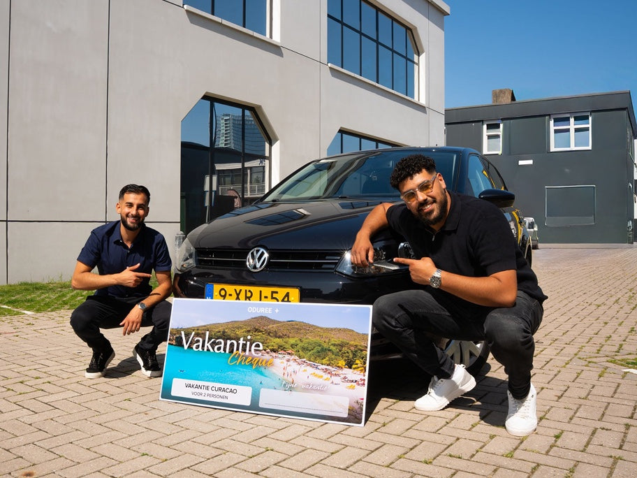 Marco en Kiro bij de Volkswagen Polo met de vakantiecheque voor een reis naar Curaçao