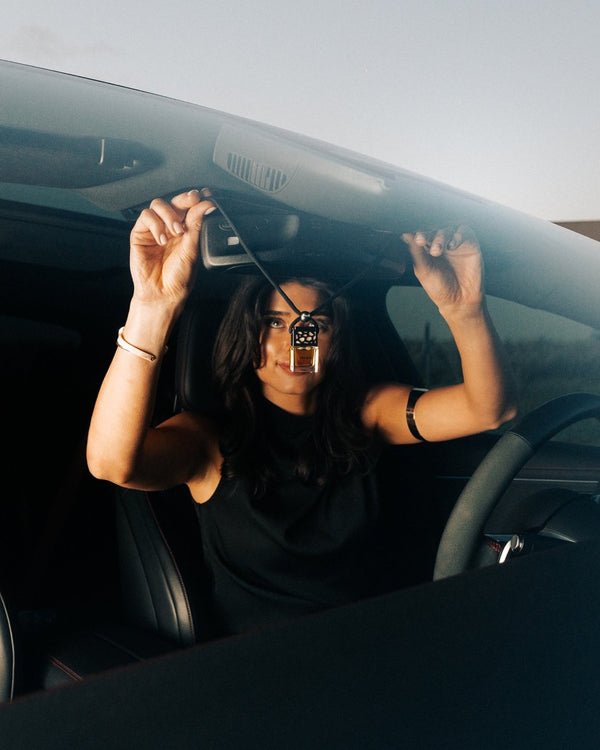 The bottle is hung from the rear-view mirror
